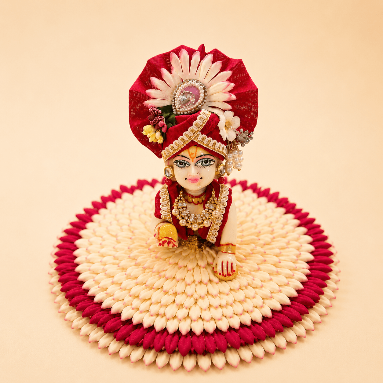Laddu Gopal dressed in a crimson wagha with pearl pagh, seated on a flower asan